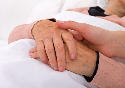 Caregiver holding elderly patients hand at home