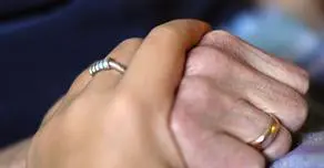 Close up view of a caretaker holding the hands of a patient