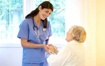 Nurse having a relaxing conversation and holding an elder woman's hand